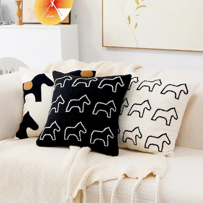 Des coussins décoratifs de couleurs sombres et contrastées, ornés de motifs de silhouettes animales, apportent une touche moderne et graphique à l'ambiance du salon.