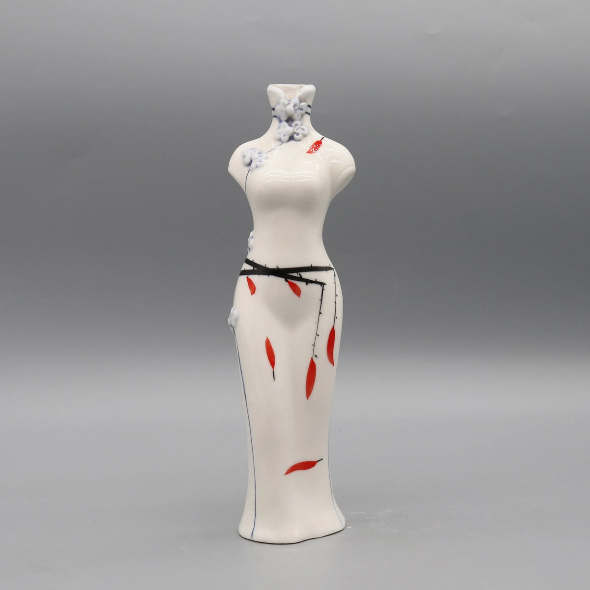 Figurine féminine en porcelaine blanche décorée de motifs floraux bleu ciel et de détails rouges.