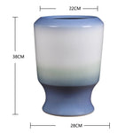 Vase décoratif en céramique au dégradé de couleurs bleu et blanc, de forme cylindrique avec un col évasé, mesurant environ 38 cm de hauteur pour 22 cm de diamètre.