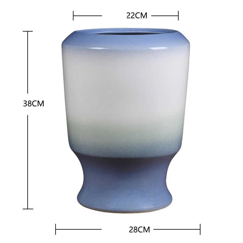 Vase décoratif en céramique au dégradé de couleurs bleu et blanc, de forme cylindrique avec un col évasé, mesurant environ 38 cm de hauteur pour 22 cm de diamètre.