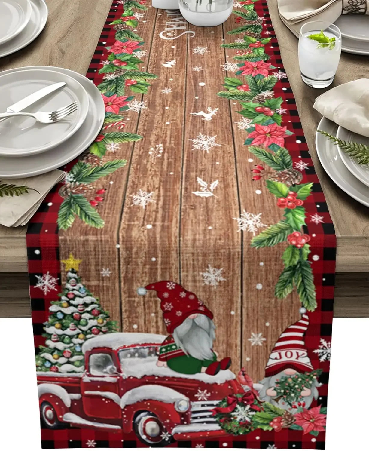Chemin de table de Noël avec des motifs de houx, de flocons de neige et de camions rouges vintage sur un fond en bois.