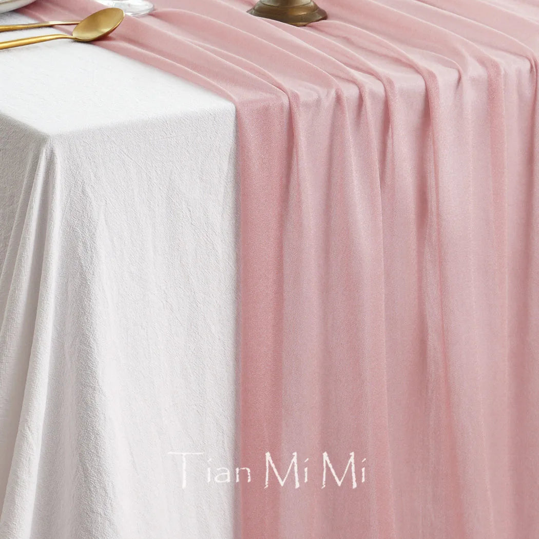 Nappe blanche et rose pastel disposée sur une table de dîner, avec des couverts dorés.