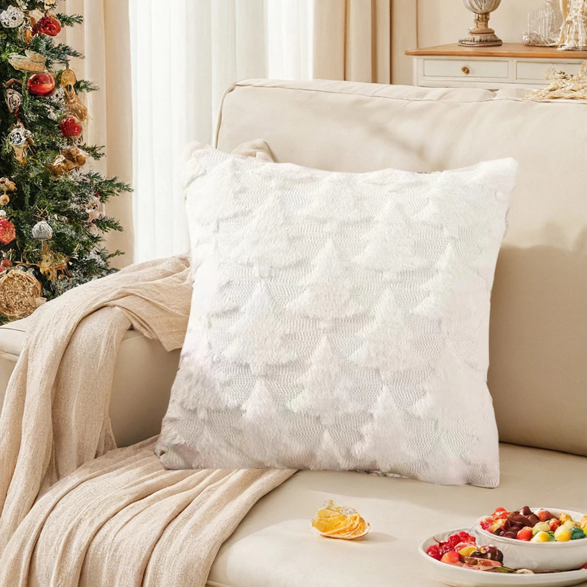 Une élégante décoration de Noël avec un oreiller décoratif blanc et une assiette de fruits festifs posés sur un sofa crème dans un intérieur confortable et douillet.