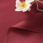 Fleur blanche élégante posée sur un fond soyeux rouge foncé avec des motifs délicats.