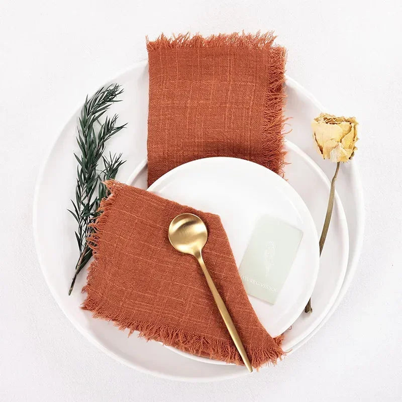 serviette table carrée orange franges moderne élégante fourchettes cuillères assiettesbranches séchées guirlande bougie parfumée