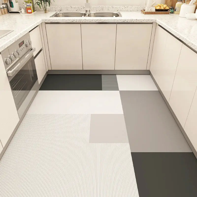 Un sol de cuisine moderne composé de dalles grises et blanches aux motifs graphiques, complétant harmonieusement les armoires beiges et le plan de travail en granite.