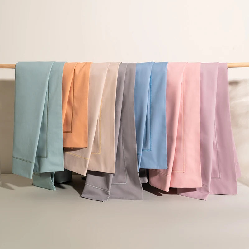 Variété de draps de lit dans des couleurs pastels douces, suspendus sur une barre métallique.