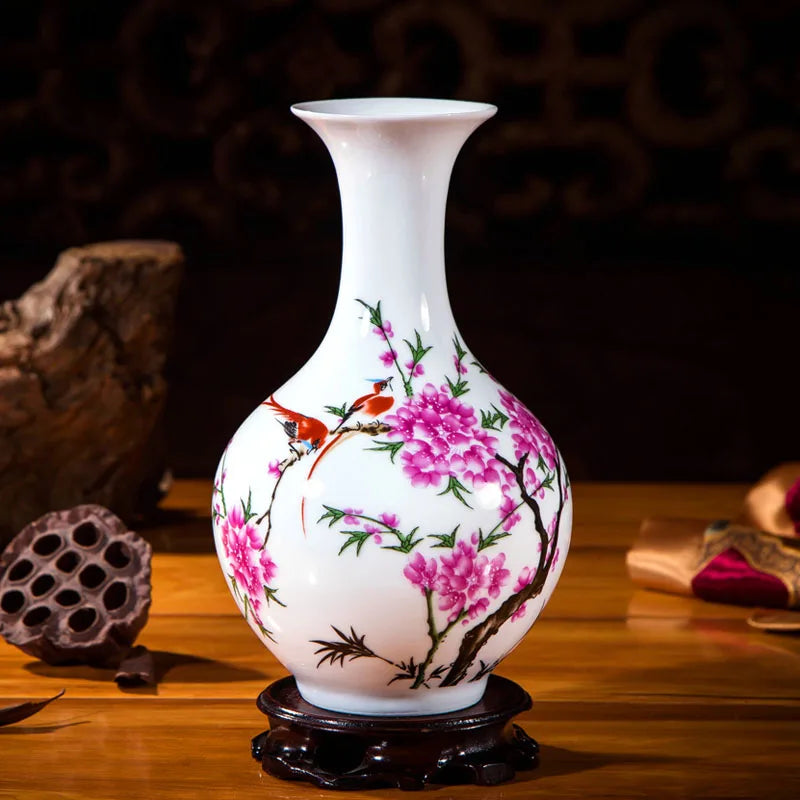 Vase de porcelaine blanche orné de fleurs de pruniers et d'oiseaux peints avec soin, posé sur un socle en bois foncé.