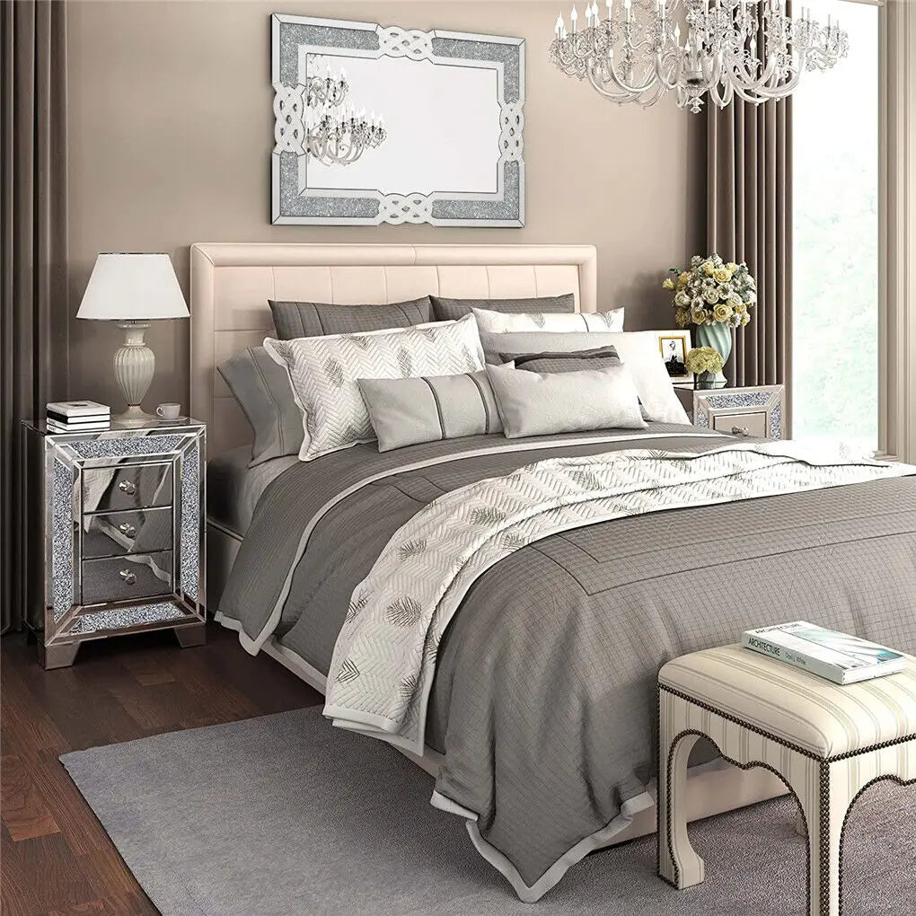 Une chambre à coucher élégante avec un lit capitonné, des tables de chevet en miroir et de luxueux luminaires en cristal.