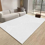 Un tapis géométrique blanc et gris dans un salon moderne avec un canapé et des accessoires décoratifs.
