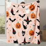 Couverture Halloween avec motifs de citrouilles, chats noirs, fantômes et chauves-souris sur un fond rose.