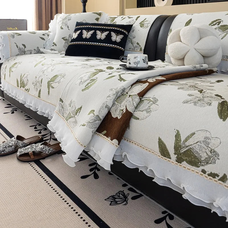 Un lit douillet décoré d'un linge de lit blanc et vert avec des motifs floraux délicats, complété par des coussins et des accessoires de style bohème.