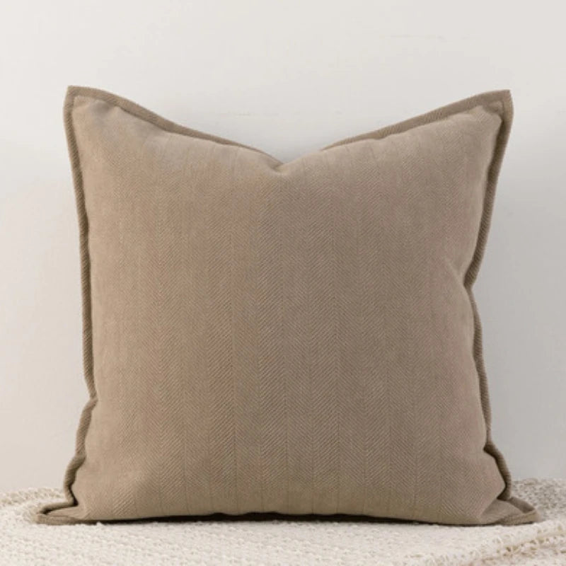 Coussin décoratif beige en tissu de qualité avec un motif en chevrons, qui apporte une touche de sophistication à l'ameublement.