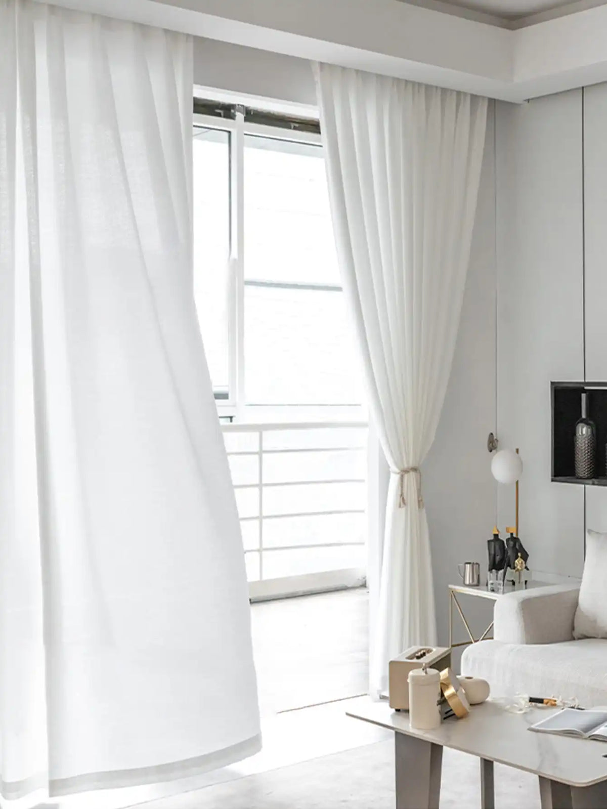 Voilage blanc léger pour salon flottant devant une grande fenêtre.