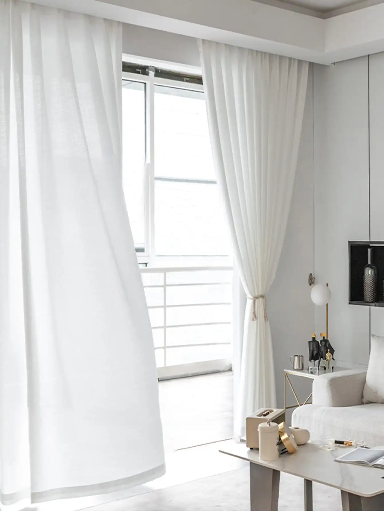 Voilage blanc léger pour salon flottant devant une grande fenêtre.