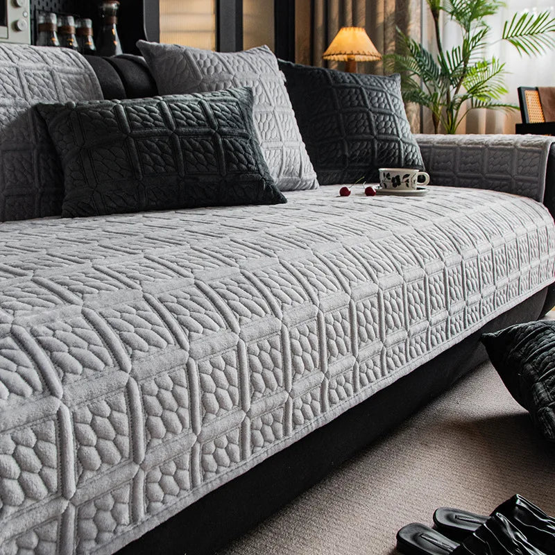 Une vaste causeuse gris foncé, ornée de motifs géométriques élégants, se trouve dans un salon cosy et bien aménagé.