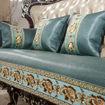 Canapé luxueux avec de riches broderies dorées sur un rembourrage vert émeraude, créant une atmosphère élégante et raffinée.