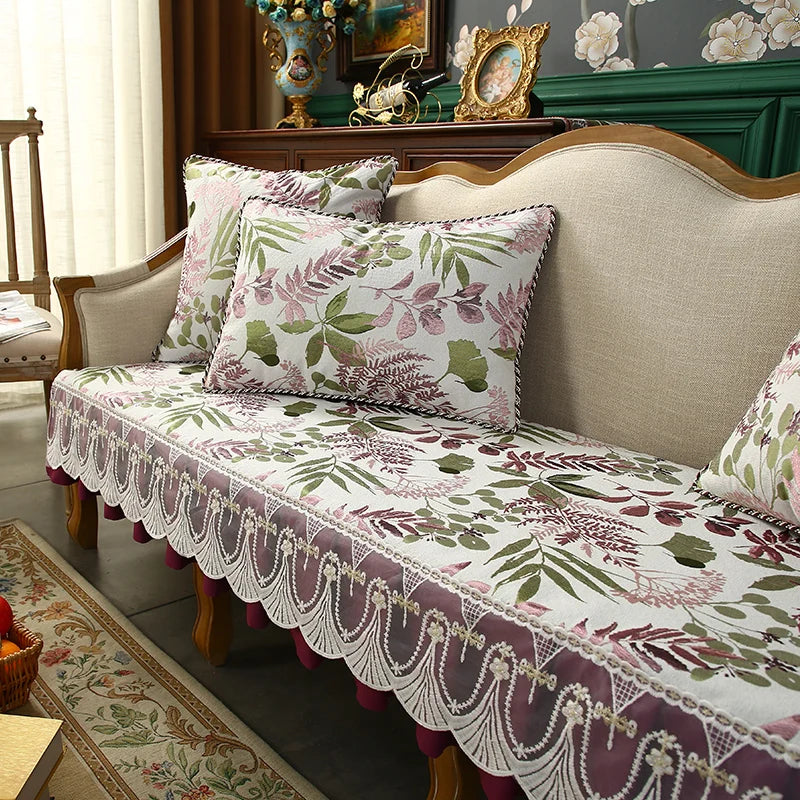 Un canapé décoré de magnifiques coussins aux motifs de feuilles vertes, de fleurs et d'accents mauves, rehaussant l'élégance et le charme de cette pièce de mobilier.