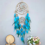 Magnifique attrape-rêves artisanal aux nuances de bleu et de turquoise, orné de perles dorées et de plumes gracieuses, créant une atmosphère apaisante et mystique.