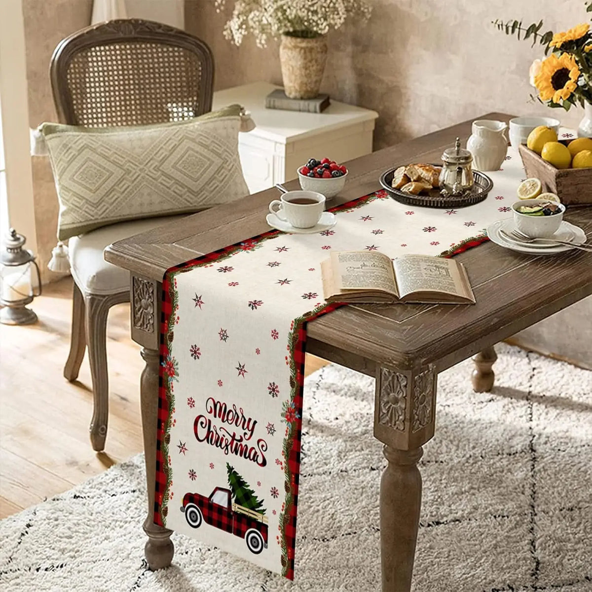 Table décorée avec des éléments de Noël, incluant une nappe motif flocon de neige, une tasse de thé, des viennoiseries et un livre ouvert, le tout dans une ambiance chaleureuse et festive.