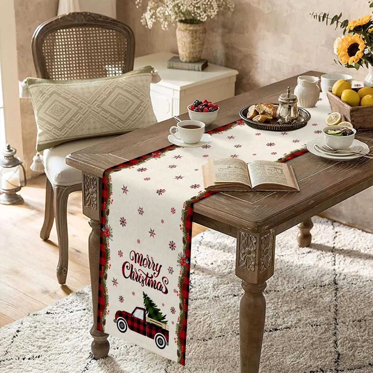 Table décorée avec des éléments de Noël, incluant une nappe motif flocon de neige, une tasse de thé, des viennoiseries et un livre ouvert, le tout dans une ambiance chaleureuse et festive.