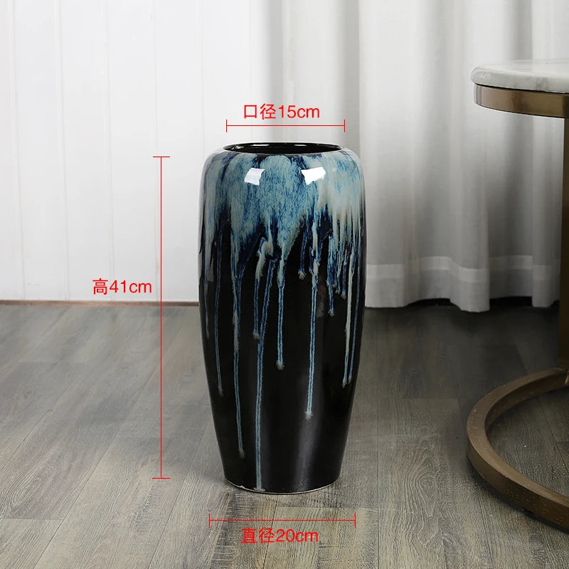 Un vase de style céramique bleu et noir aux couleurs nuancées, posé sur un sol en bois, mesurant 41 cm de hauteur et 15 cm de diamètre.