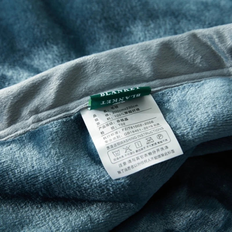 L'image montre une étiquette apposée sur un vêtement en tissu gris, indiquant les informations techniques et de lavage du produit.