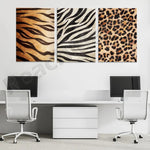 Ensemble de trois imprimés décoratifs aux motifs de fourrure d'animal, composé de rayures de zèbre, de tigre et de léopard, sur un mur blanc dans un bureau avec deux chaises de bureau blanches et un meuble de rangement.