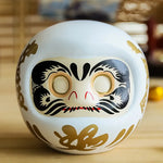 statuette japonaise daruma rouge blanche visage sourire yeux grands ouverts motifs dorés traditionnels décoration
