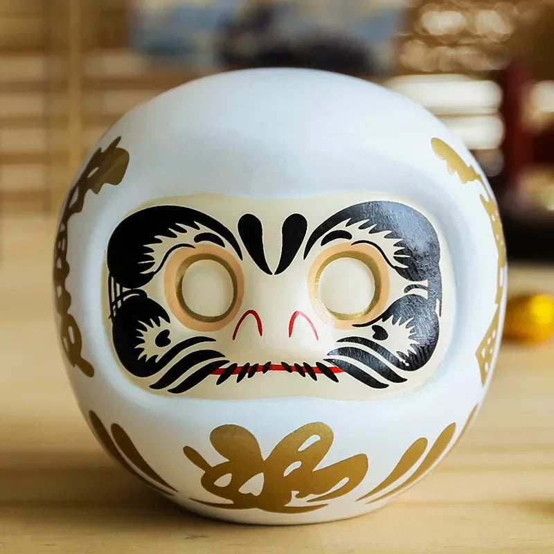 statuette japonaise daruma rouge blanche visage sourire yeux grands ouverts motifs dorés traditionnels décoration