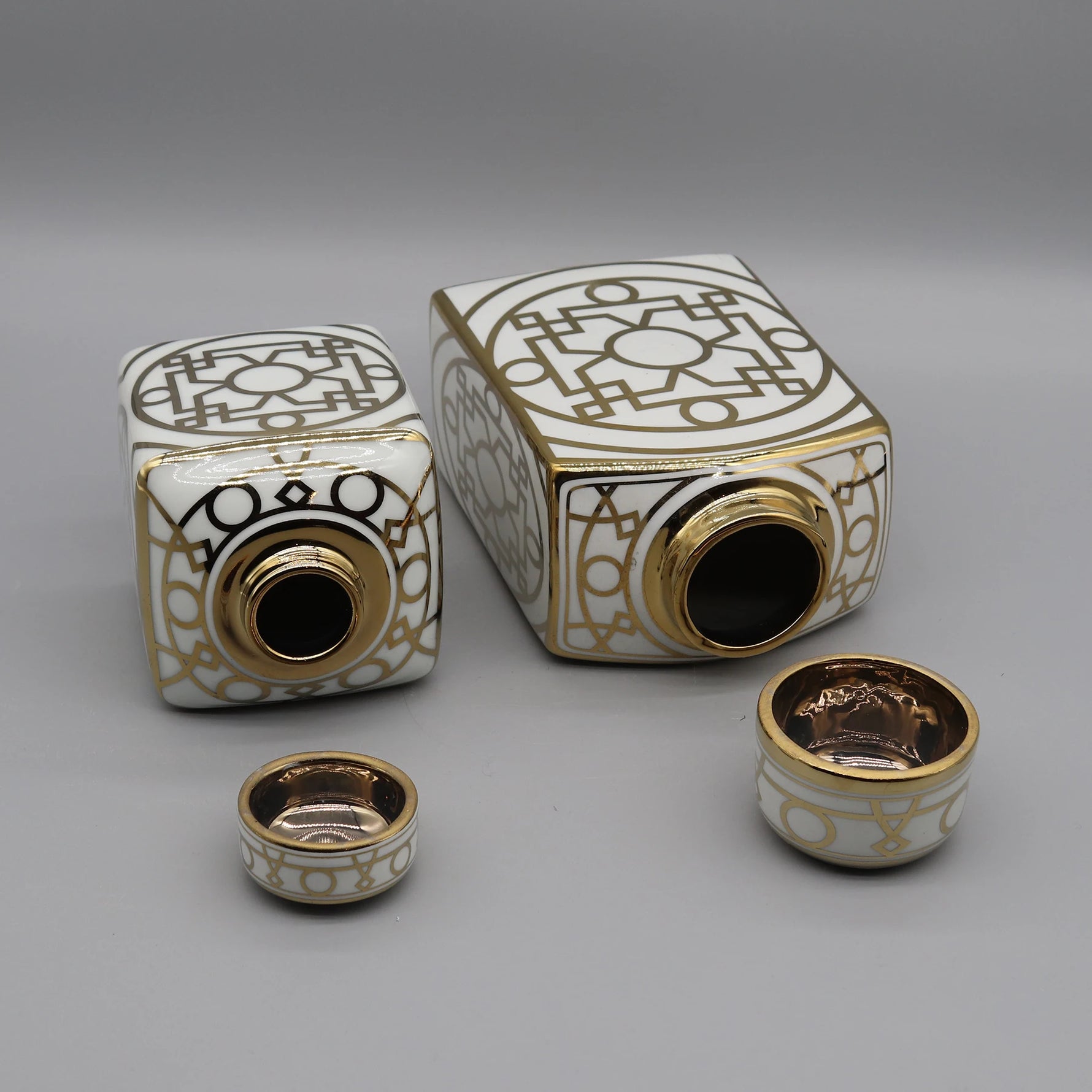 Ensemble décoratif de vases ornés de motifs géométriques dorés sur un fond blanc, créant une esthétique élégante et raffinée.