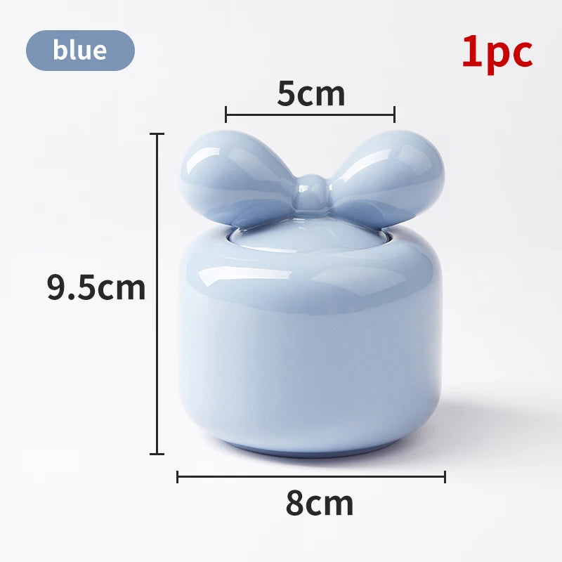 Un récipient décoratif bleu clair de 9,5 cm de hauteur et 8 cm de largeur, surmonté d'un nœud élégant.