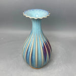 Un vase en céramique de forme élégante, avec des couleurs bleu pâle et dorées qui se mélangent de manière harmonieuse, offrant une apparence sophistiquée et décorative.