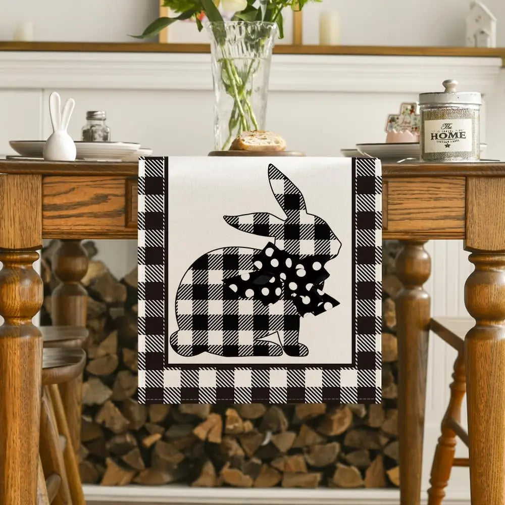 Un chemin de table avec un motif à carreaux noir et blanc montrant un lapin stylisé, posé sur une table en bois rustique avec des accessoires de décoration.