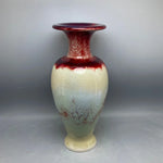 Vase de style vintage avec un fini en céramique crème et rouge, créant un effet marbré et texturé.