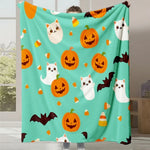 Couverture douce et colorée avec des motifs d'Halloween, chats blancs mignons et citrouilles souriantes sur un fond turquoise.