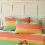 Des oreillers décoratifs dans des couleurs vives et des motifs géométriques ornent un espace de vie élégant avec un mur blanc aux panneaux sculptés.