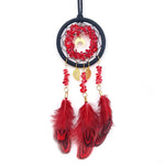 Un attrape-rêves décoratif avec un cercle noir, des pierres rouges et des plumes rouges ornées de feuilles dorées.
