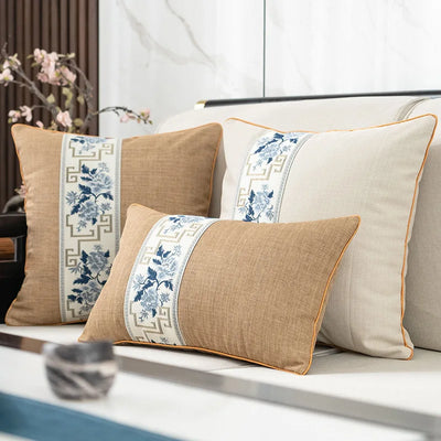 Des coussins décoratifs de couleurs beige et bleu ornés de motifs floraux élégants, disposés sur un canapé dans un décor moderne et raffiné.