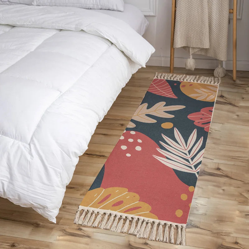 Un tapis coloré et motif tropical avec des franges, placé au pied du lit dans une chambre à coucher blanche et confortable.