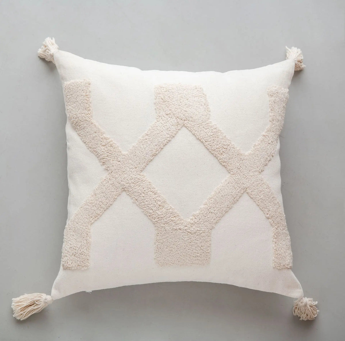 Coussin décoratif blanc avec des motifs en relief en forme de losanges en beige.