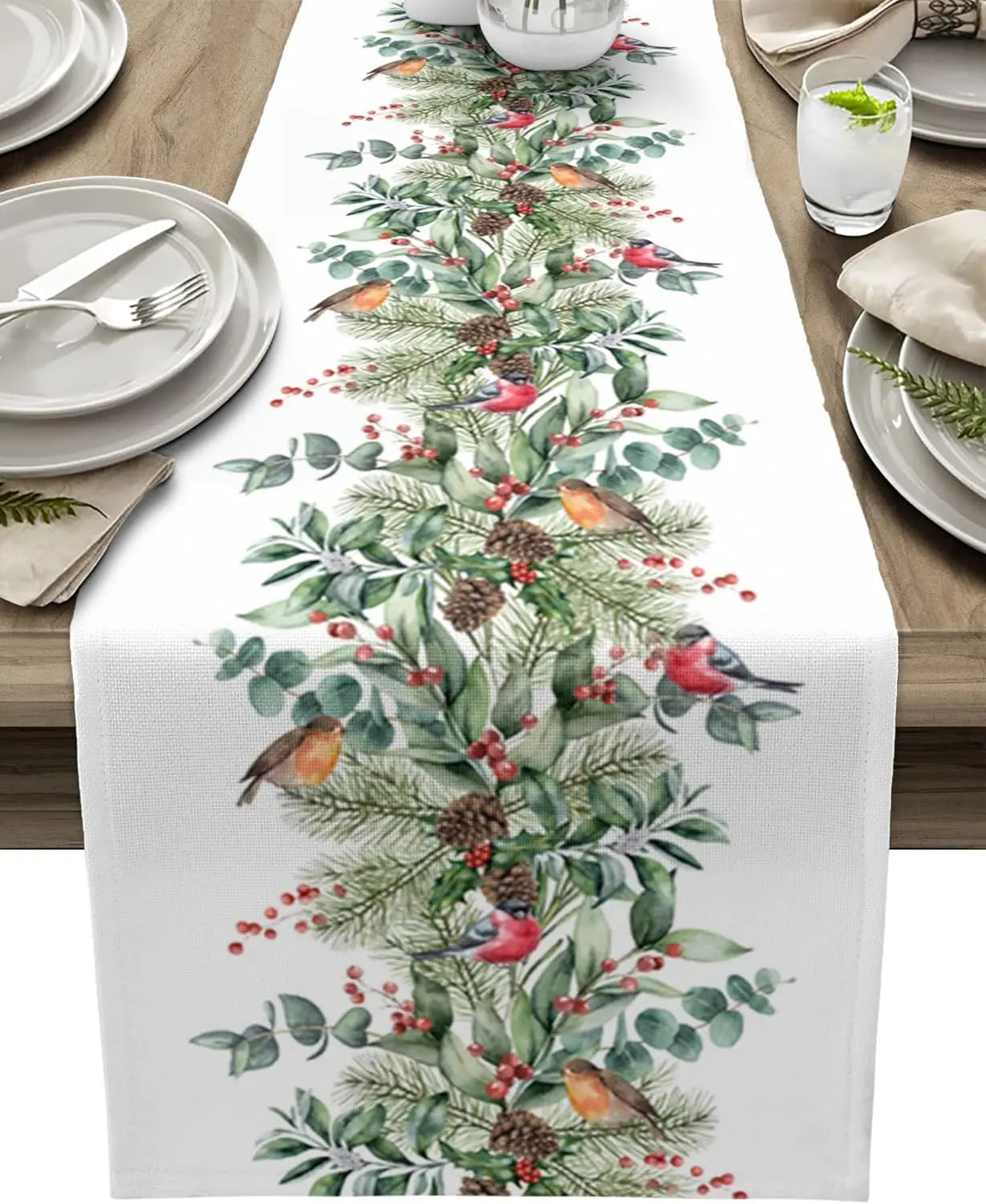 Une table élégante avec une nappe blanche ornée d'un motif végétal coloré et animé de petits oiseaux, soulignant l'esprit festif de la saison.