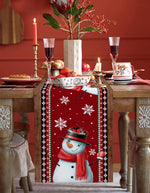Table de Noël festive avec décorations en rouge et blanc, bougies allumées, coupes de vin et fleurs rouges dans un vase.