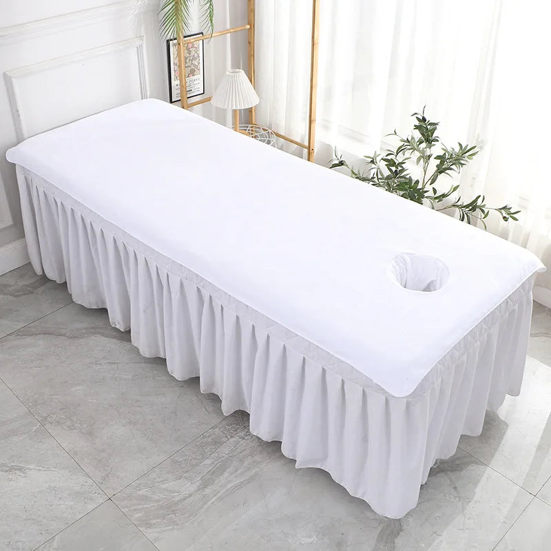 Une table de massage blanche élégante et moderne, entourée d'un rideau blanc et accueillante dans cette pièce lumineuse.