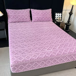 Couverture de lit rose pâle de style contemporain avec un motif géométrique répété sur toute la surface.