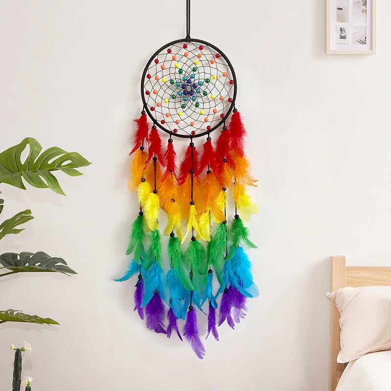 Un magnifique capteur de rêves multicolore, composé d'un cercle tressé de motifs géométriques et orné de longues plumes vibrant dans des teintes arc-en-ciel, suspendu au mur dans un intérieur lumineux.