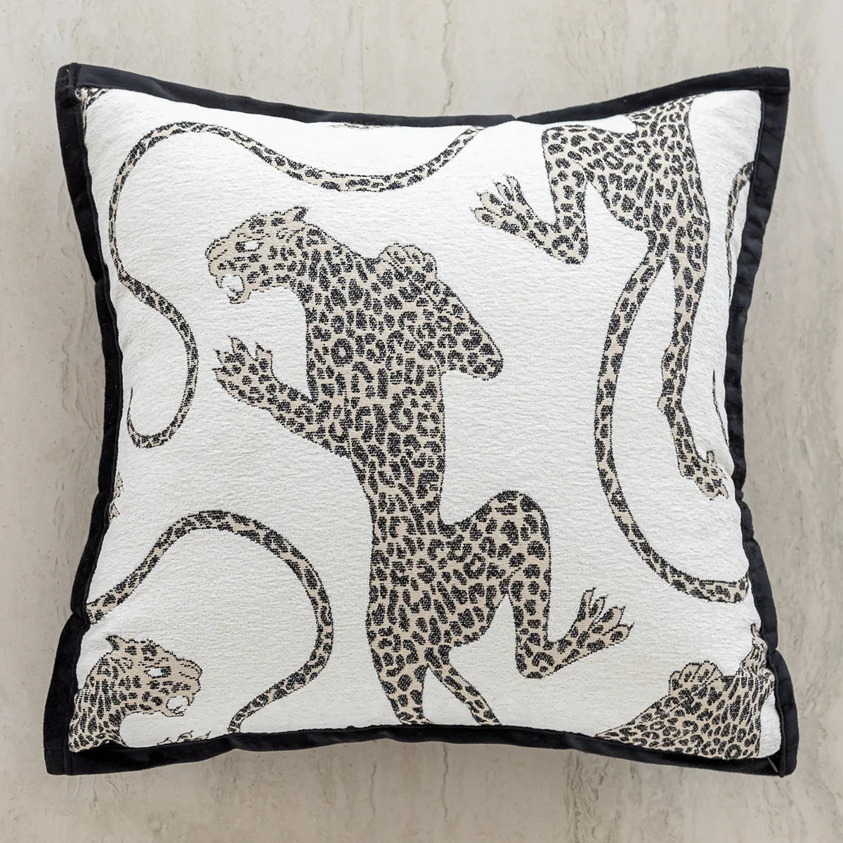 Coussin orné d'un motif de félins tachetés en noir et blanc, évoquant un style animal print.