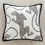 Coussin orné d'un motif de félins tachetés en noir et blanc, évoquant un style animal print.