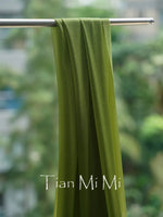 Une serviette verte suspendue sur une barre métallique avec l'inscription "Tian Mi Mi" imprimée.
