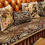 Coussins décoratifs colorés sur un canapé richement orné de motifs floraux et paisley.